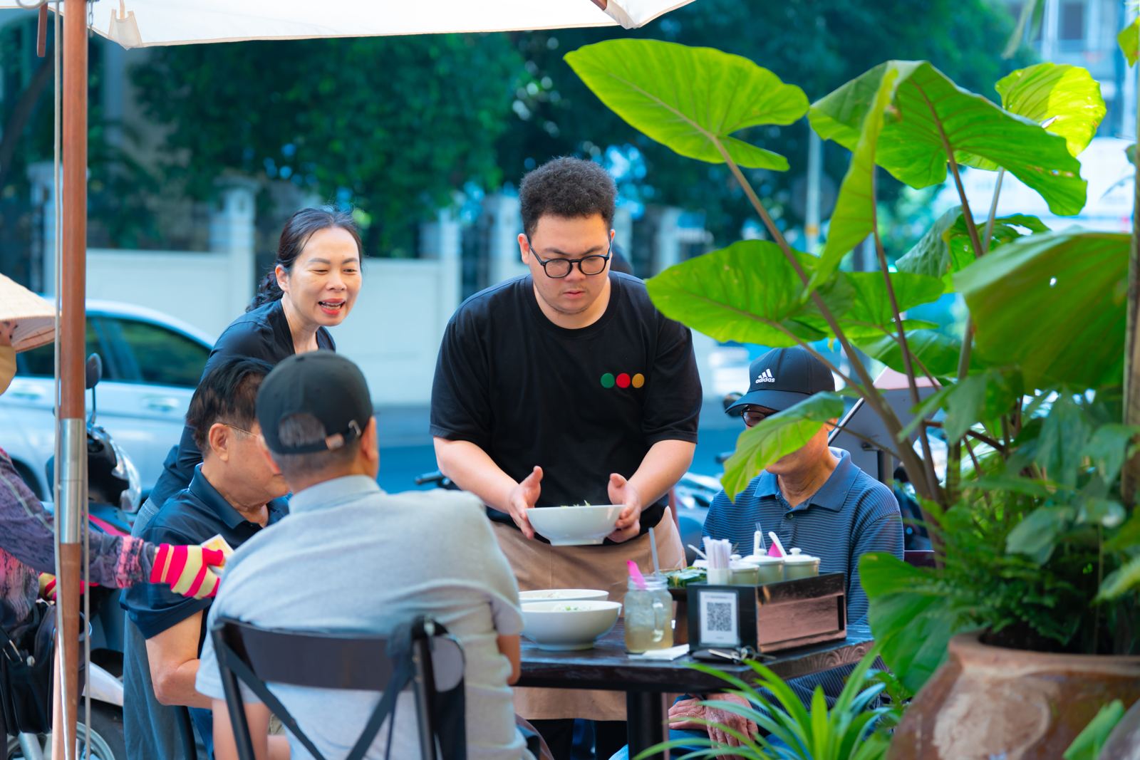 Nhân viên mang bún bò ra bàn ngoài hiên